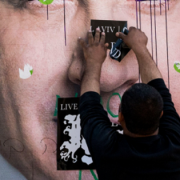 A man puts a sticker on a vandalized campaign poster of PM Benjamin Netanyahu. Photo: Danielle Shitrit/Flash90