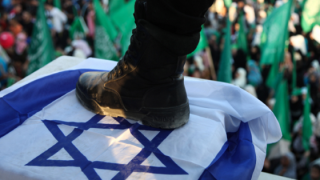 A militant of the Ezzedeen Al-Qassam Brigades steps on an Israeli flag in front of Hamas supporters at a rally in Gaza City, Wednesday, Aug. 27, 2014. Photo: Emad Nassar/Flash90A militant of the Ezzedeen Al-Qassam Brigades steps on an Israeli flag in front of Hamas supporters at a rally in Gaza City, Wednesday, Aug. 27, 2014. Photo: Emad Nassar/Flash90